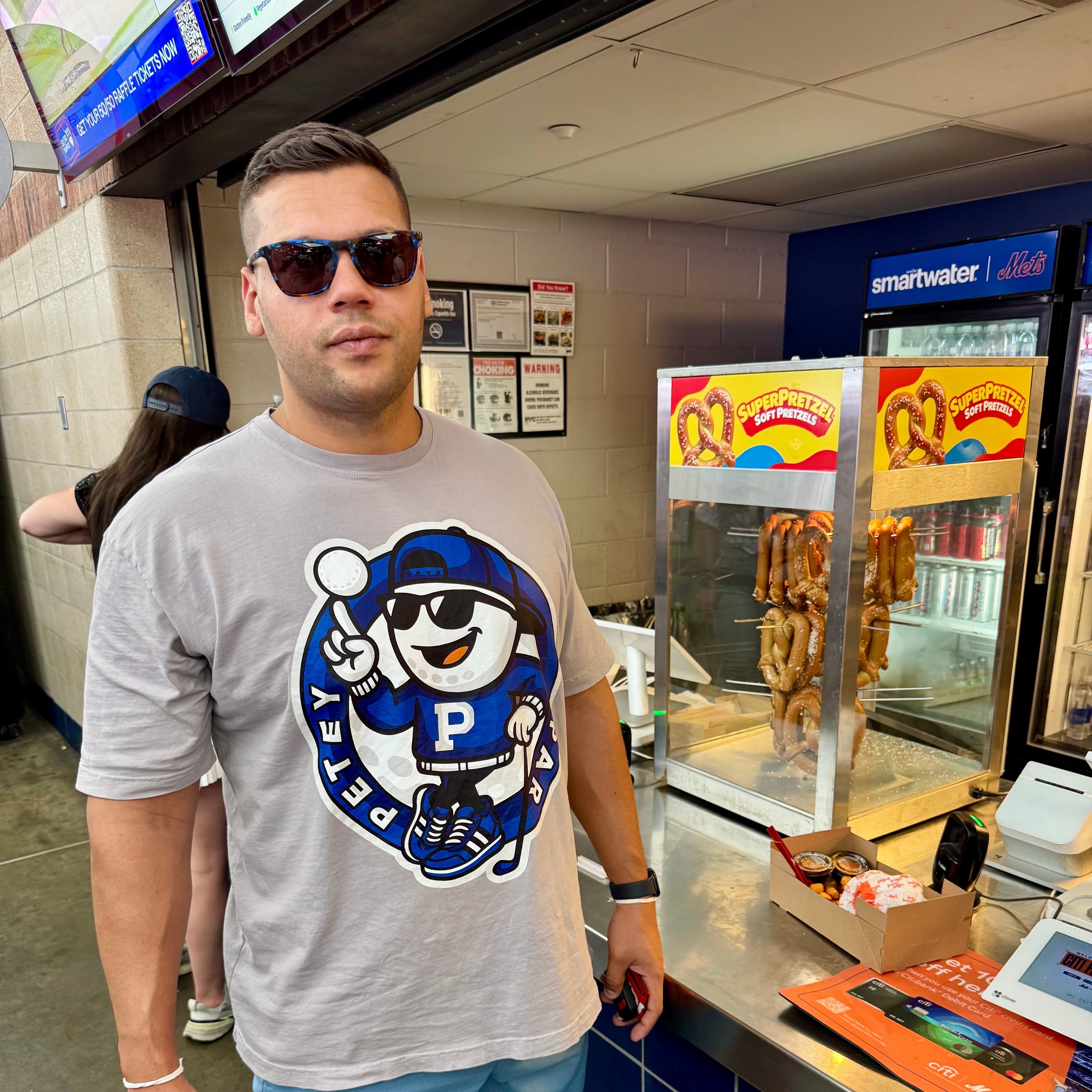 Man wearing a gray t-shirt with a logo, standing in a fast-food restaurant.